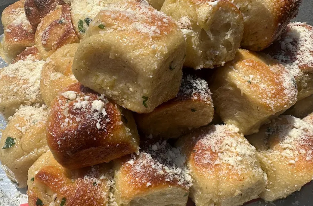 Pile of golden garlic knots topped with garlic, herbs, and Parmesan from Fusaro’s Pizza & Pasta