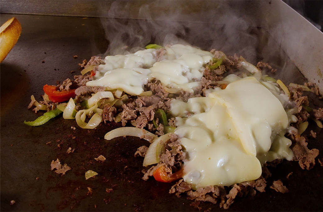 Steak being chopped on the griddle for a cheesesteak at Fusaro's